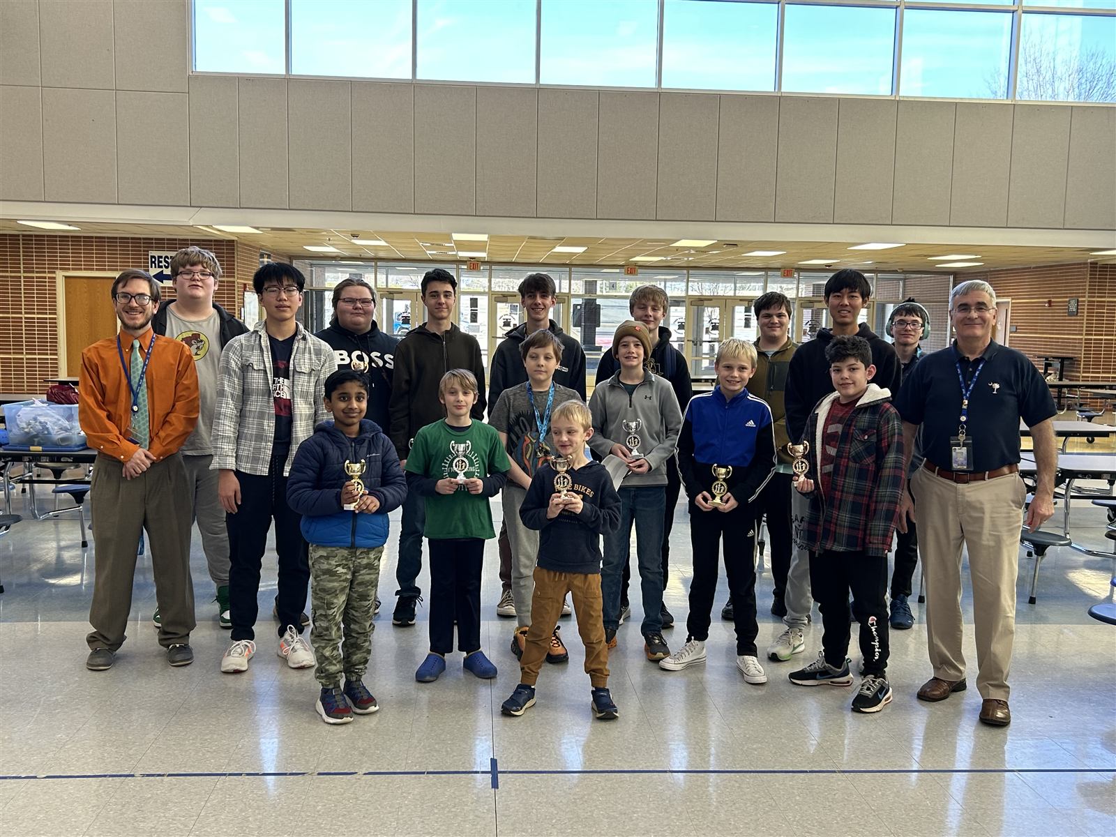 A group of student chess tournament winners holding trophies